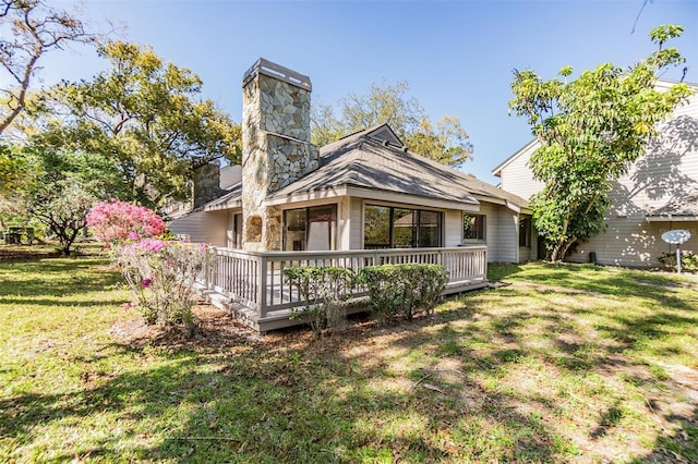 rear view of house featuring a wooden deck, a lawn, and a chimney