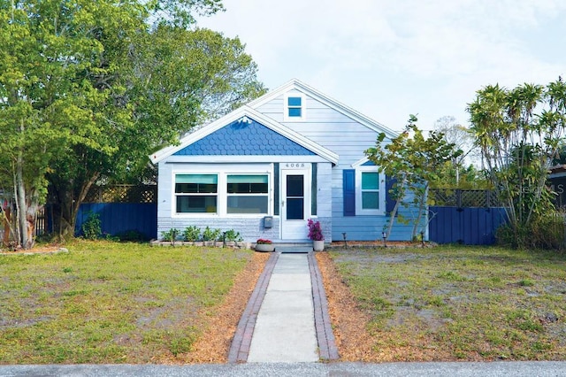 bungalow with a front yard and fence