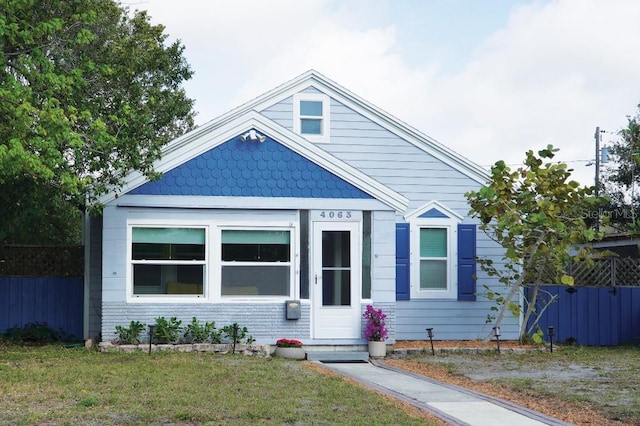 bungalow with a front yard and fence