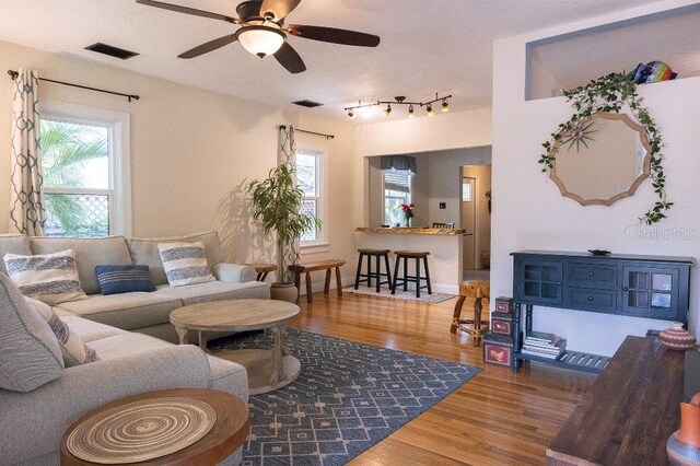 living room featuring visible vents, plenty of natural light, a textured ceiling, and wood finished floors