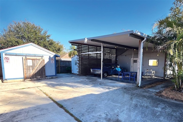 view of parking with driveway, a shed, and fence