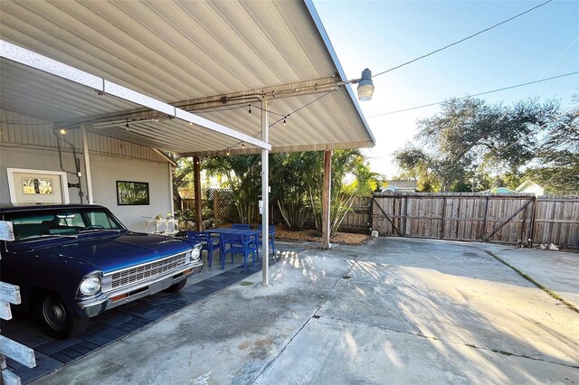 garage with a gate, fence, and a carport