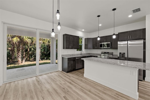 kitchen with light stone counters, visible vents, appliances with stainless steel finishes, light wood-type flooring, and a center island