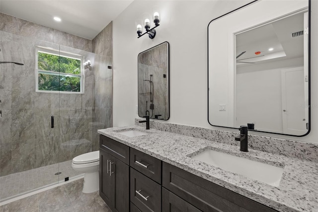 bathroom featuring toilet, a shower stall, double vanity, and a sink