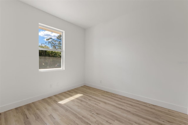 spare room featuring light wood-type flooring and baseboards