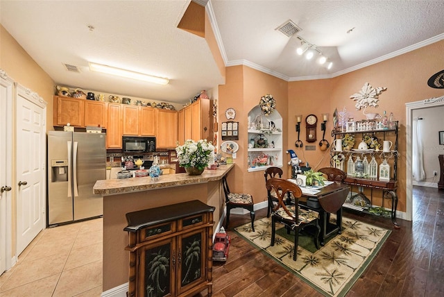 10017 Courtney Palms Blvd Unit 301, Tampa, FL 33619 - kitchen with stainless steel fridge, black microwave, a peninsula, crown molding, and a textured ceiling