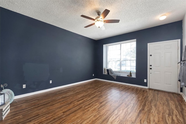 empty room with a ceiling fan, wood finished floors, baseboards, and a textured ceiling