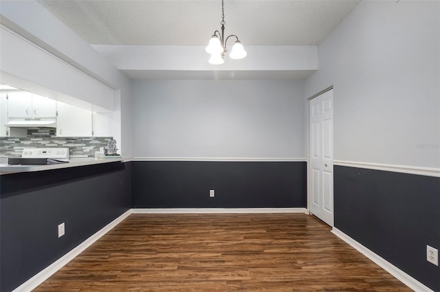 unfurnished dining area with dark wood finished floors, baseboards, and a chandelier