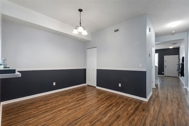 empty room with baseboards, wood finished floors, visible vents, and a textured ceiling