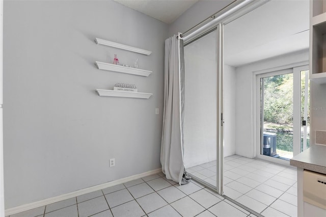 unfurnished bedroom with light tile patterned floors, a closet, baseboards, and access to exterior