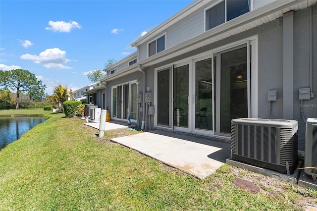 rear view of house with a patio, cooling unit, a yard, and a water view