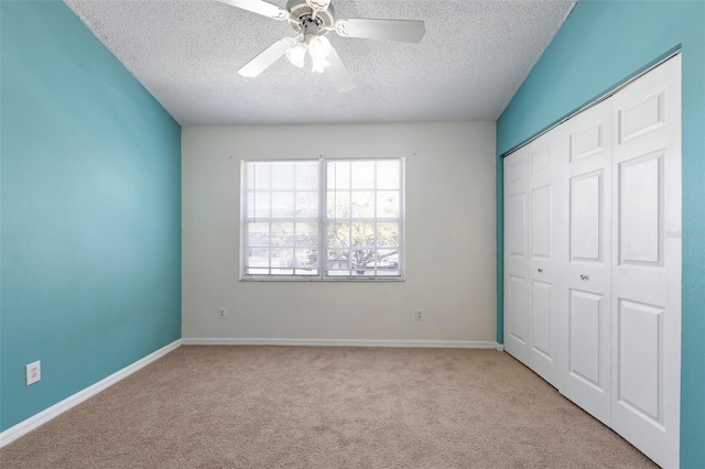 unfurnished bedroom with a closet, carpet floors, a textured ceiling, and baseboards