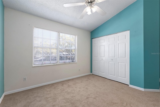 unfurnished bedroom featuring a closet, vaulted ceiling, a textured ceiling, and carpet floors