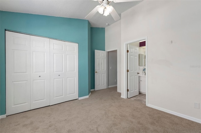 unfurnished bedroom with lofted ceiling, a closet, connected bathroom, carpet flooring, and baseboards