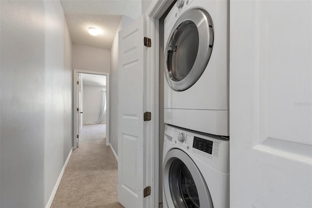 laundry area featuring carpet, baseboards, stacked washing maching and dryer, laundry area, and a textured ceiling