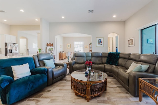 living area featuring recessed lighting, visible vents, and arched walkways