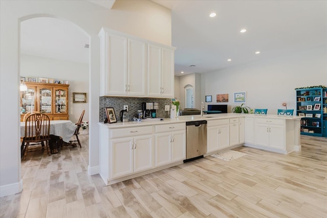 kitchen with white cabinetry, arched walkways, a peninsula, decorative backsplash, and dishwasher