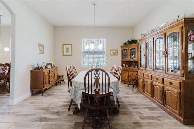 dining space featuring baseboards, arched walkways, plenty of natural light, and light wood finished floors