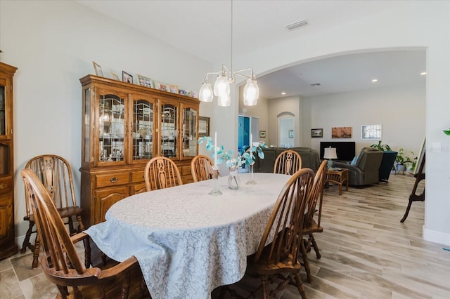 dining area with light wood-type flooring, visible vents, recessed lighting, arched walkways, and baseboards