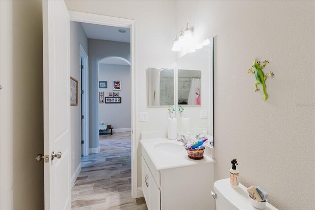 bathroom featuring toilet, vanity, baseboards, and wood finished floors