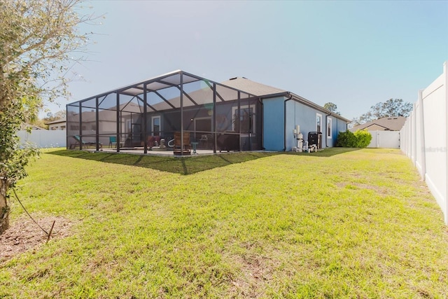 rear view of property with glass enclosure, a fenced backyard, and a lawn