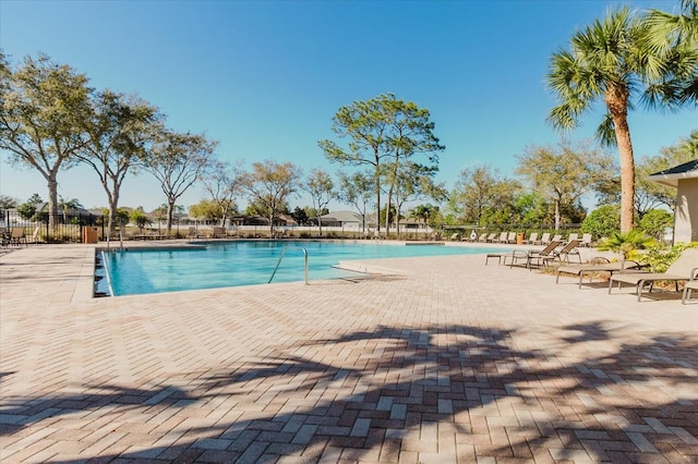 community pool with a patio and fence