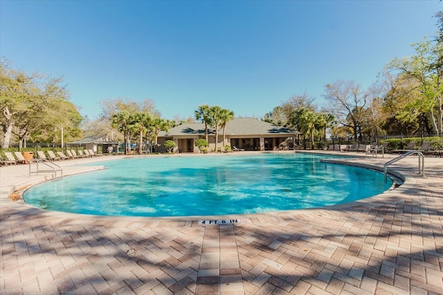 community pool with a patio and fence