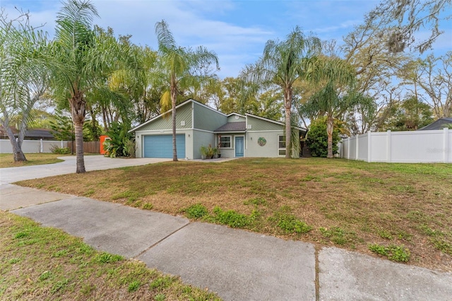 mid-century home with an attached garage, fence, concrete driveway, and a front yard