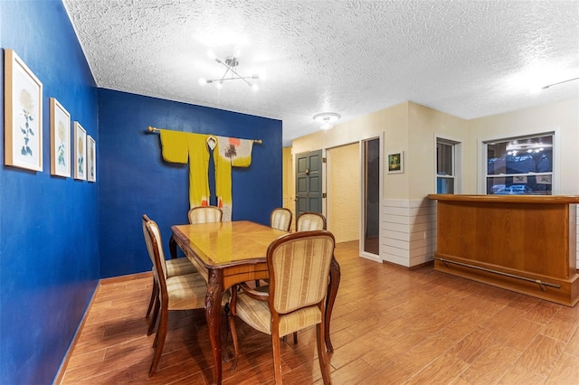 dining area with a textured ceiling, baseboards, and wood finished floors