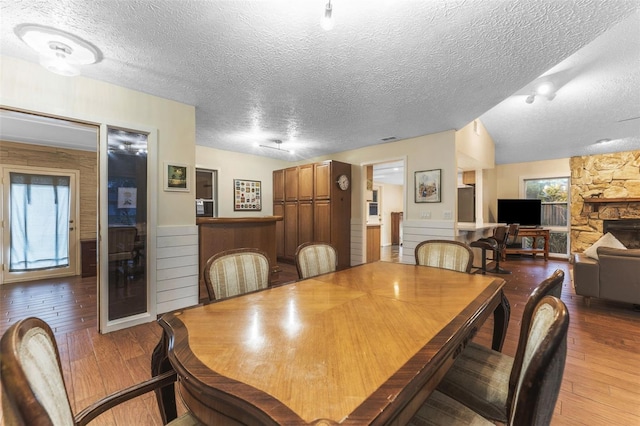 dining area featuring wood-type flooring, a textured ceiling, and a wealth of natural light