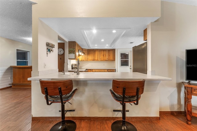 kitchen with a peninsula, a textured ceiling, appliances with stainless steel finishes, and wood finished floors