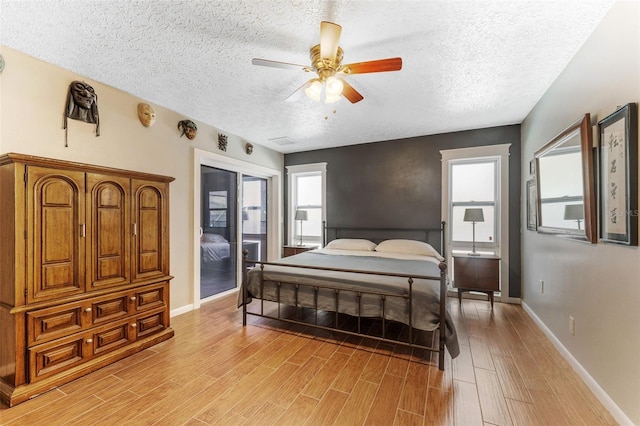 bedroom with access to exterior, wood tiled floor, a textured ceiling, and baseboards