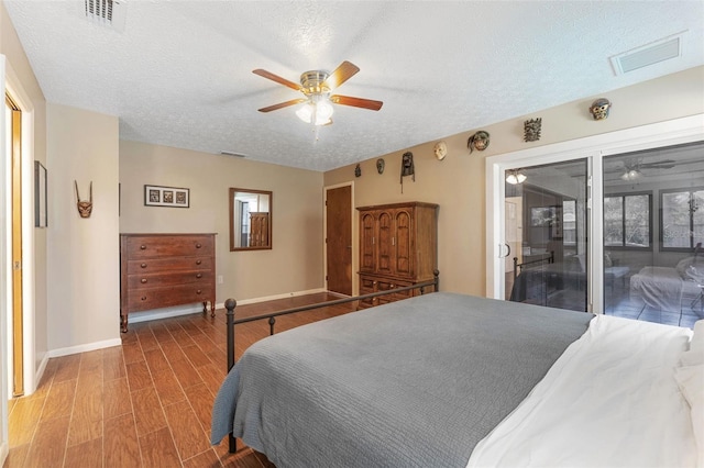 bedroom with baseboards, a textured ceiling, visible vents, and wood finished floors