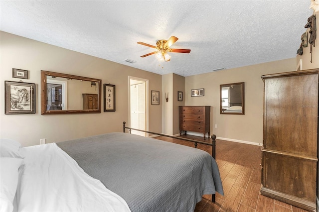 bedroom with baseboards, visible vents, a ceiling fan, wood finished floors, and a textured ceiling