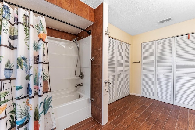 bathroom featuring wood tiled floor, a closet, a textured ceiling, and shower / bath combo with shower curtain