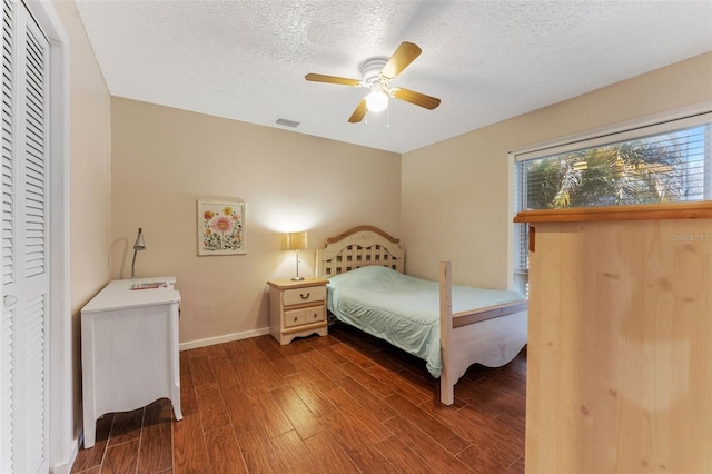 bedroom featuring visible vents, a ceiling fan, a textured ceiling, wood finished floors, and baseboards