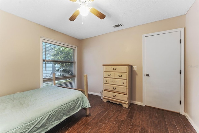 bedroom with a textured ceiling, wood finished floors, a ceiling fan, visible vents, and baseboards