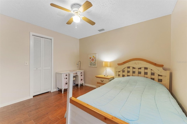 bedroom featuring a textured ceiling, wood finished floors, visible vents, and baseboards