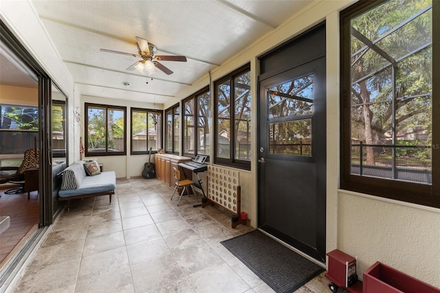 sunroom / solarium with a ceiling fan and radiator