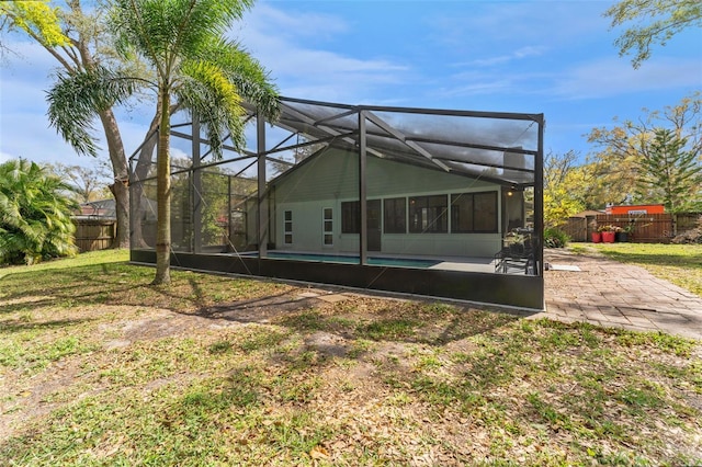 back of property featuring a yard, a patio area, fence, and a lanai