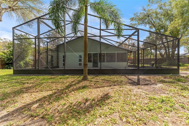 rear view of property with a lanai and fence