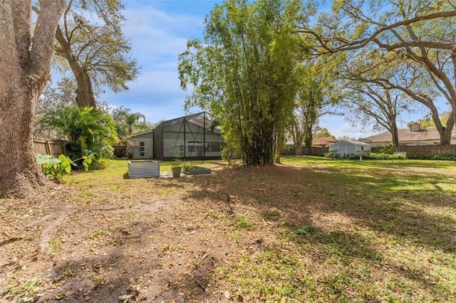 view of yard with glass enclosure and fence