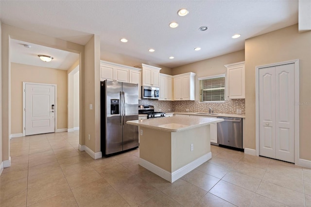 kitchen with light countertops, decorative backsplash, appliances with stainless steel finishes, a kitchen island, and a sink