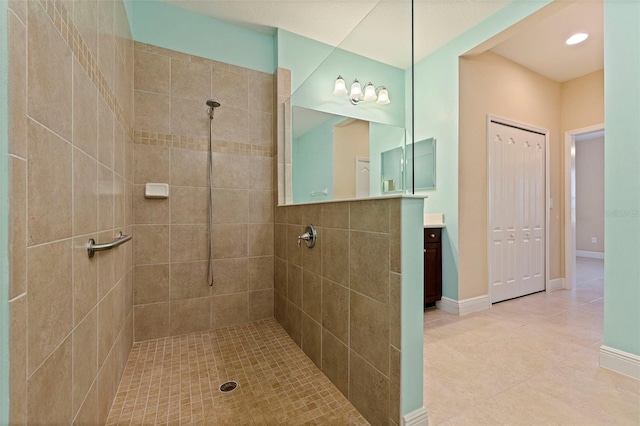 bathroom featuring tile patterned floors, baseboards, a tile shower, and vanity