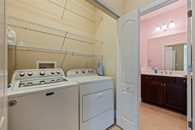 washroom with laundry area, light tile patterned floors, a sink, and separate washer and dryer