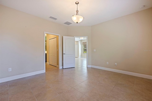 empty room featuring light tile patterned flooring, visible vents, and baseboards