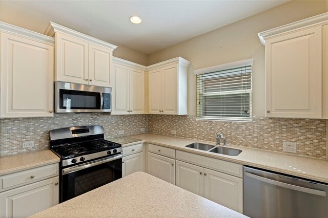 kitchen featuring stainless steel appliances, light countertops, a sink, and decorative backsplash