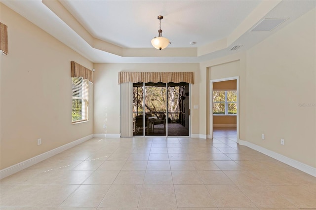 unfurnished room featuring a tray ceiling, visible vents, and plenty of natural light