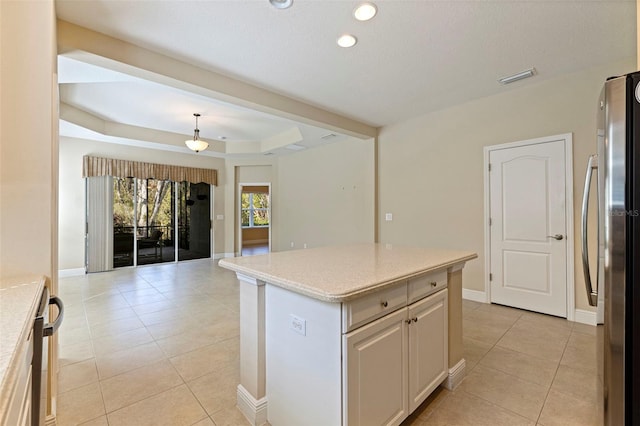 kitchen with freestanding refrigerator, a raised ceiling, visible vents, and light tile patterned floors