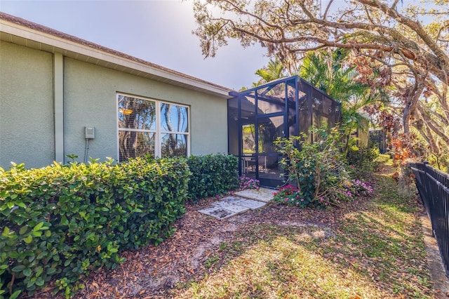 exterior space with a lanai, fence, and stucco siding